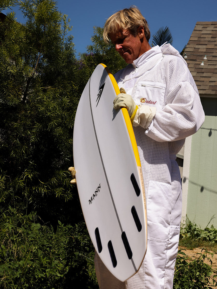 Beekeeper carrying the Firewire Spun Honey surfboard, bottom fin view