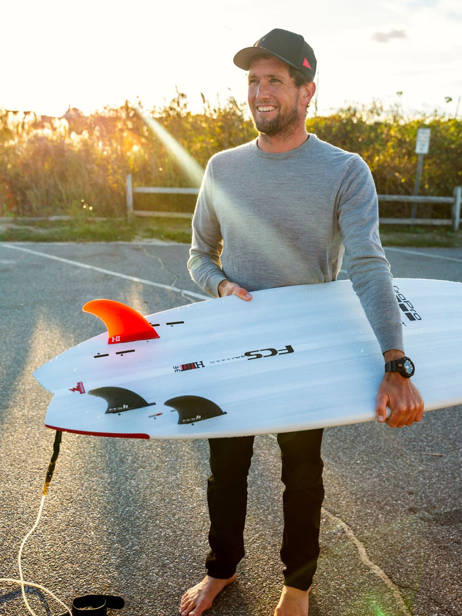 Surfer holding the HIBT 3+3 Thunderbolt surfboard, showing fin setup