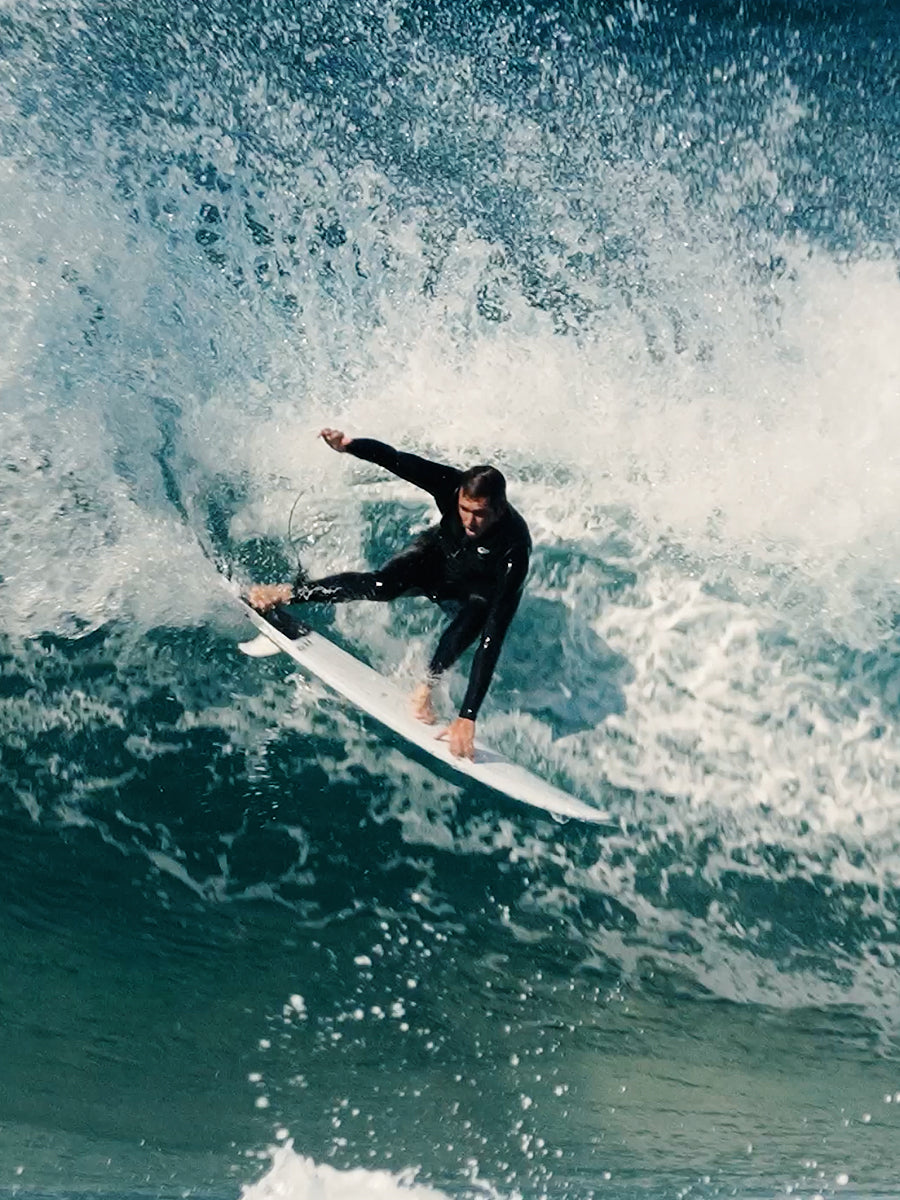 Surfer riding a wave on the HIBT 3+3 Thunderbolt surfboard